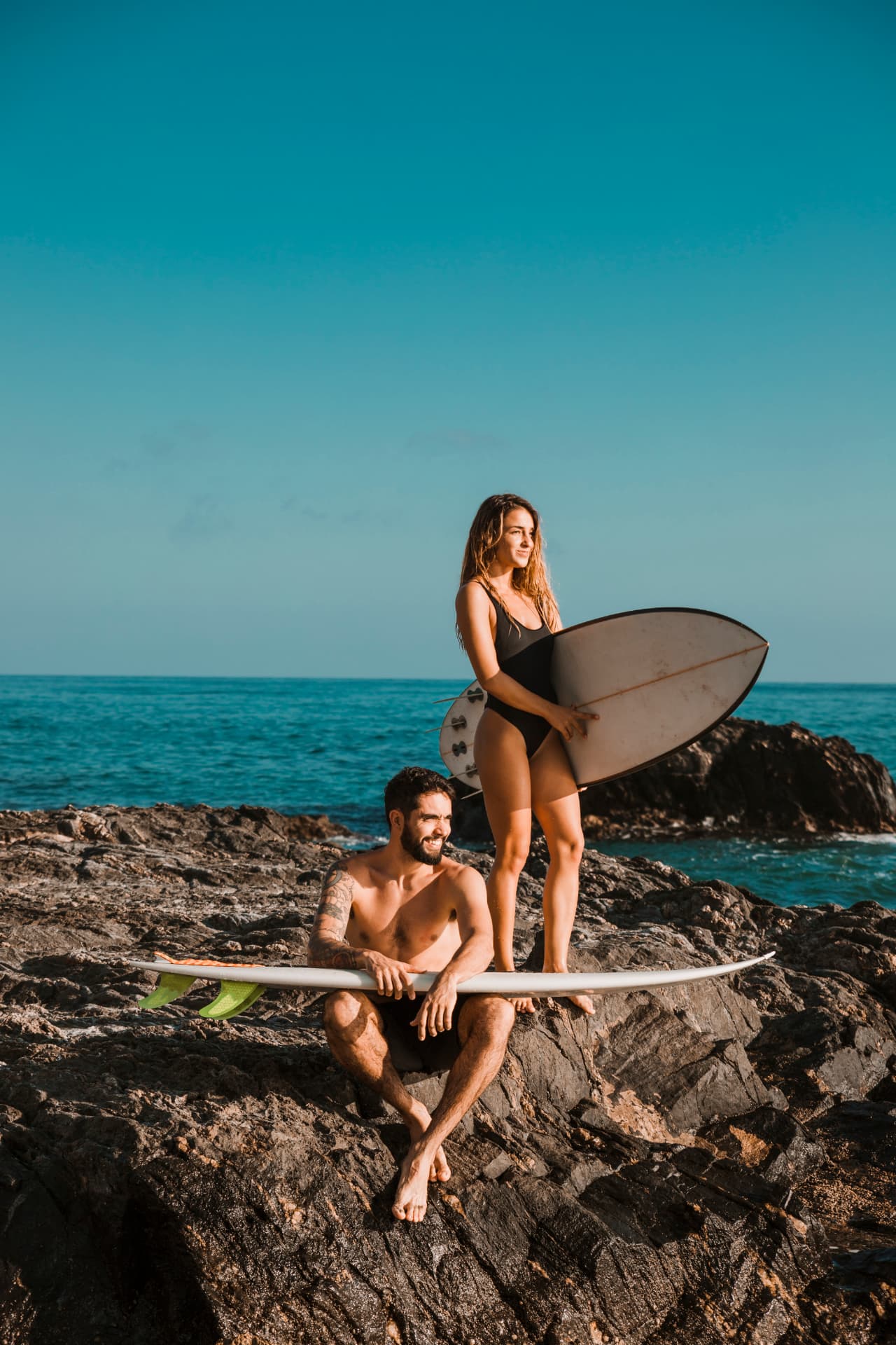 Couple de surfeurs posant sur les rochers