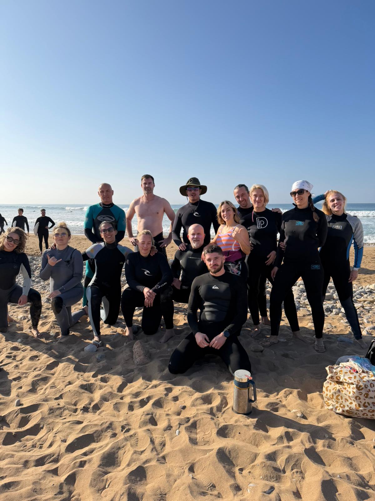 Grande groupe de surfeurs posant sur la plage après la session