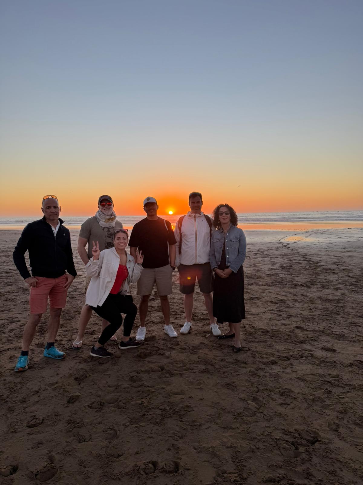 Groupe de surfeurs posant au coucher du soleil sur la plage de Tamraght