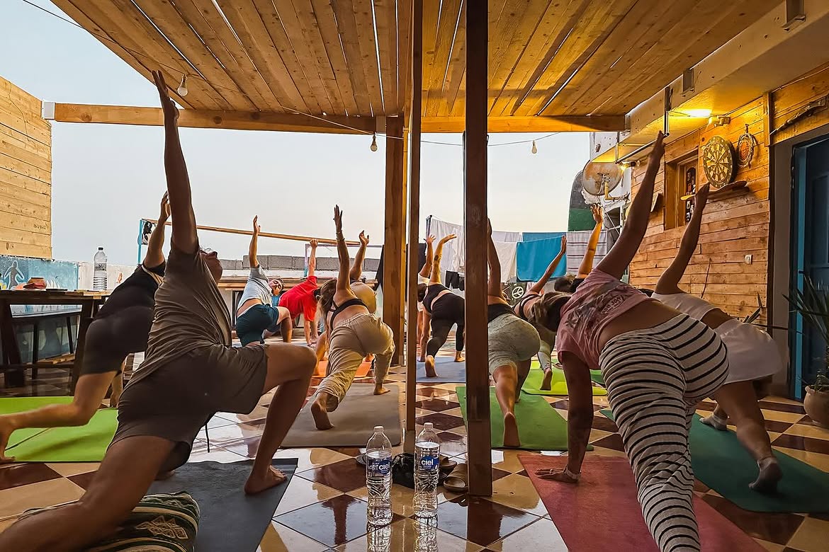 Groupe de yogis sur le rooftop au coucher de soleil à Taghazout