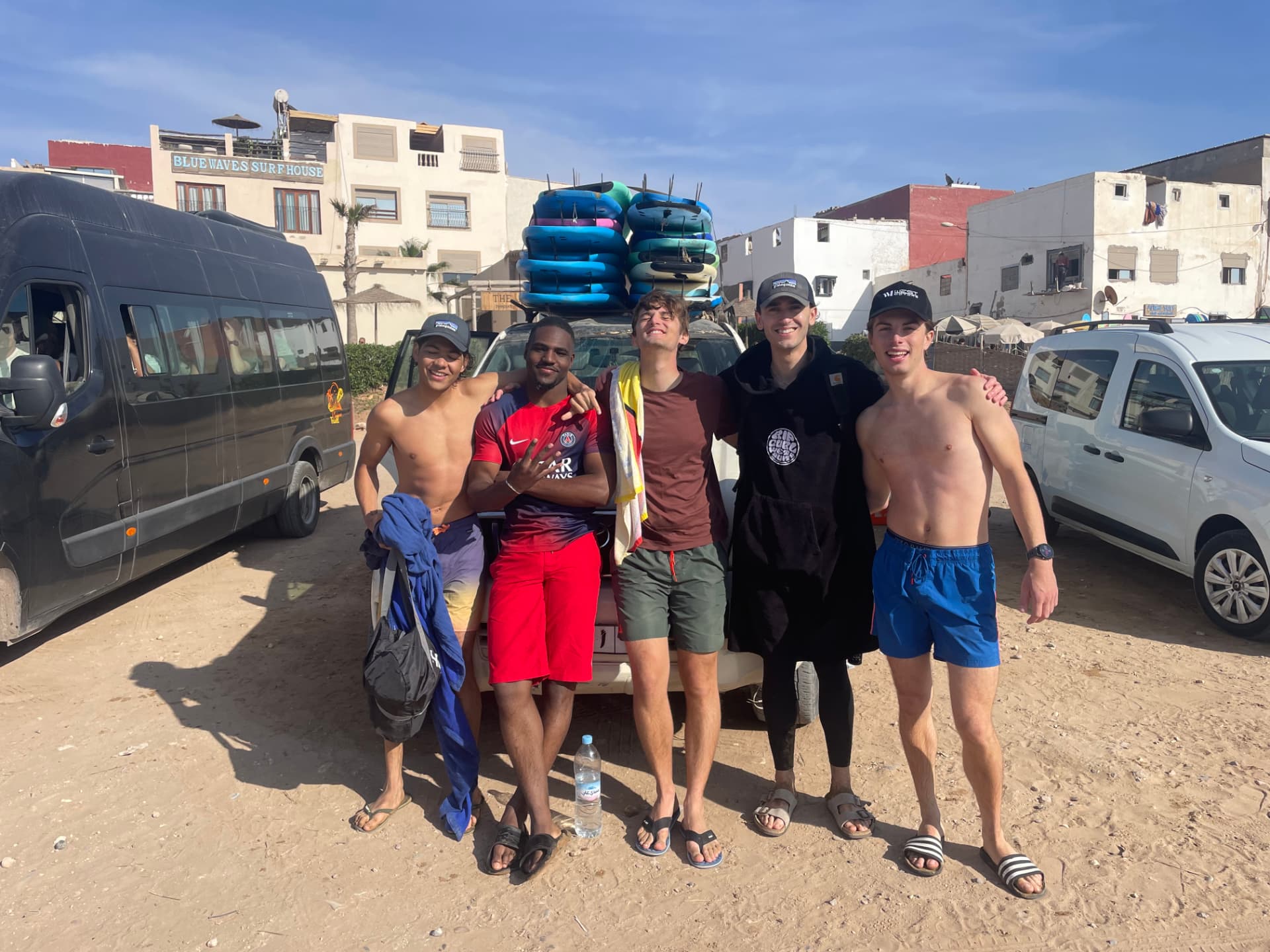 Groupe de surfeurs posant devant la voiture WAVESKY chargée de planches à Taghazout