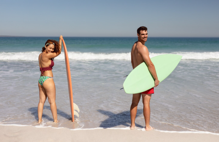 Couple avec planches de surf sur la plage