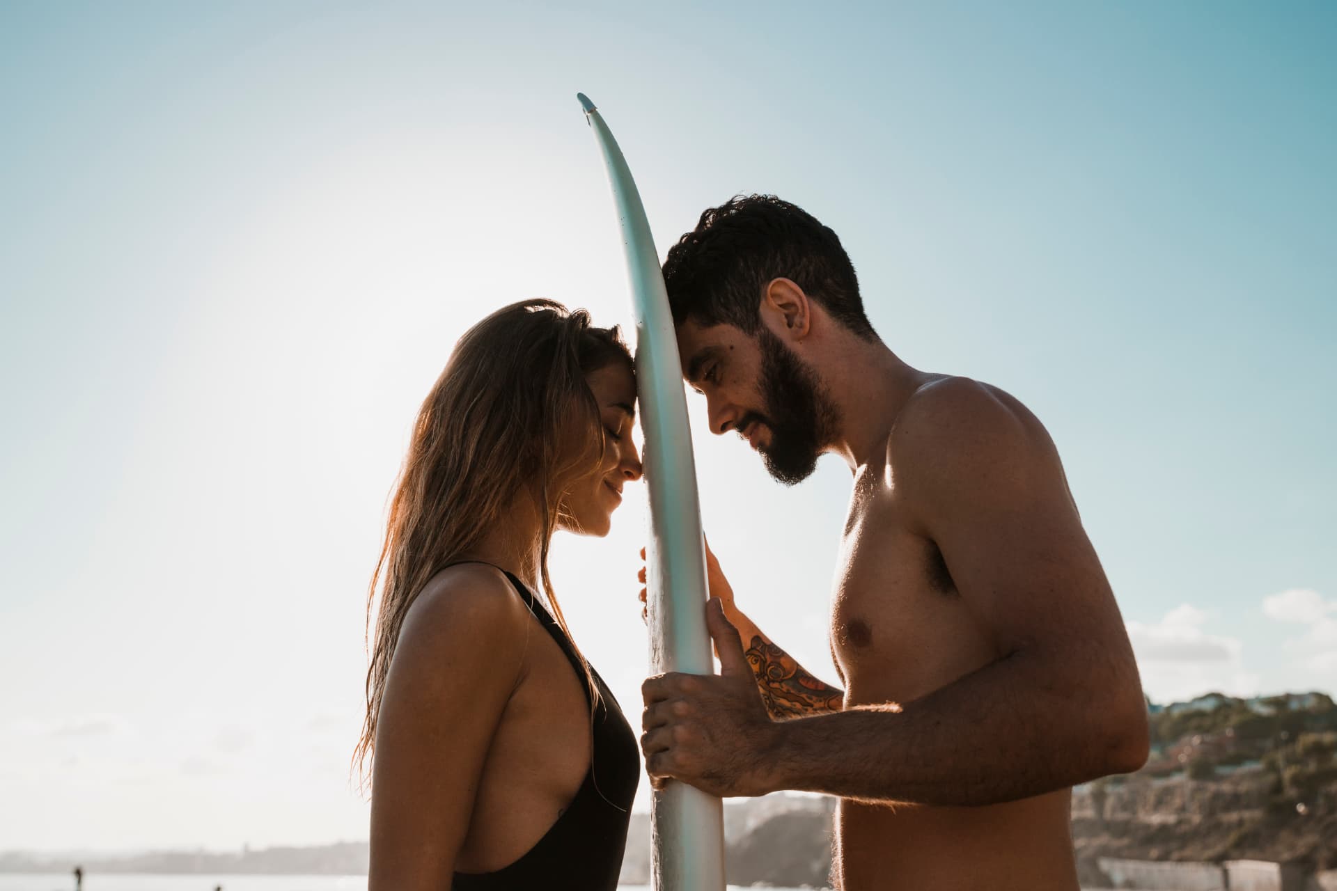 Couple avec planche de surf au coucher du soleil
