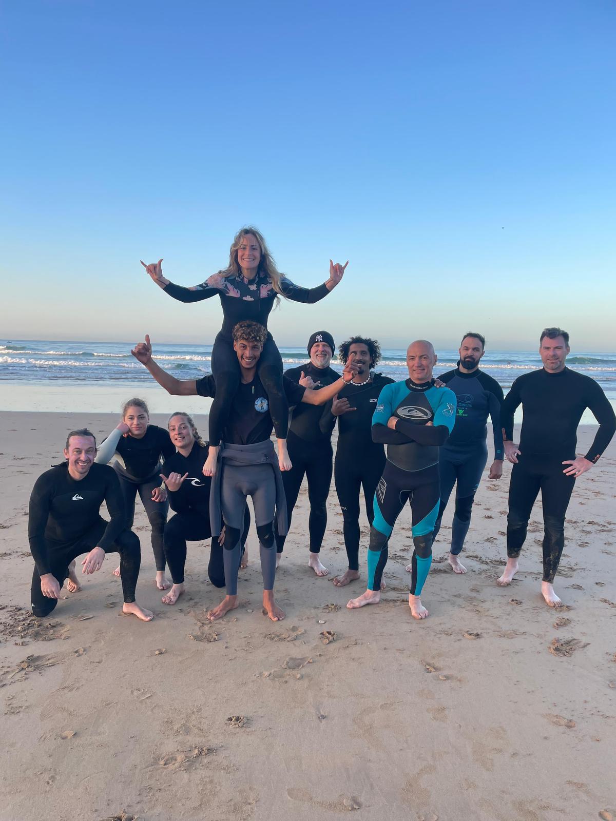 Groupe de surfeurs heureux en combinaison sur la plage